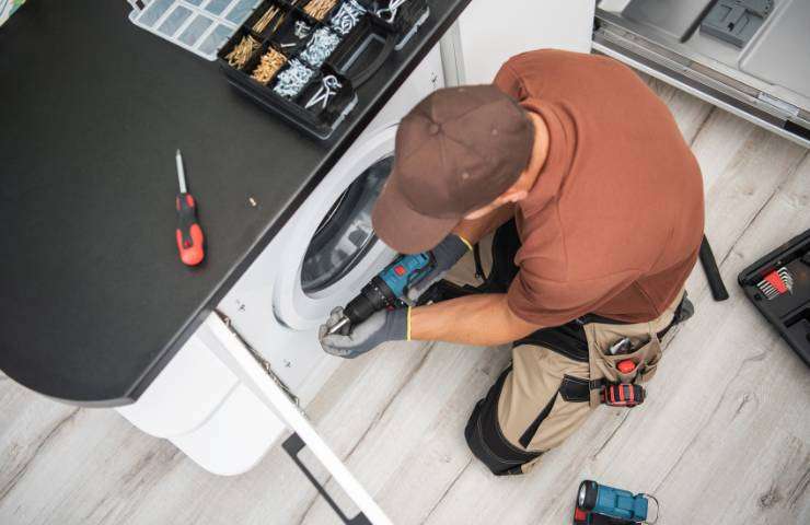 Tecnico intento alla riparazione di una lavatrice
