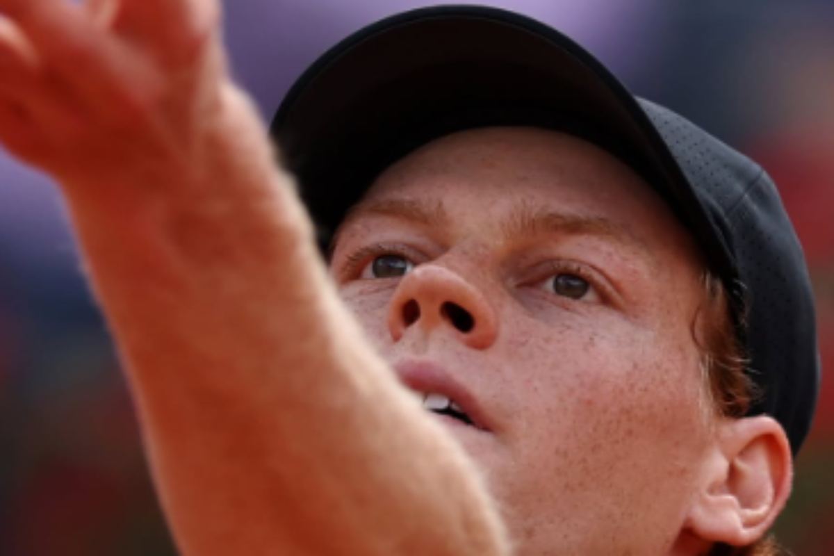 Un primo piano di Jannik Sinner intento a battere al servizio in campo.